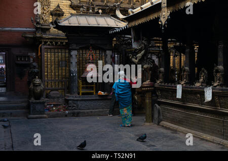 Kathmandu, Nepal - Gennaio 15, 2016: Una donna anziana nei locali del tempio d'oro a Patan a pagare il suo omaggio. Foto Stock