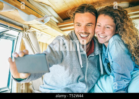 Felice l'uomo e la donna prendendo un selfie con un mobile smart phone fotocamera - Viaggiare giovane rendendo le foto del loro viaggio su un minivan vintage Foto Stock