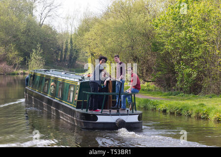 Gruppo di ragazzi britannici si stendono insieme a narrowboat viaggiando lungo il canale britannico. Vacanza in barca al sole di primavera. Divertirsi al sole. Staycation UK. Foto Stock