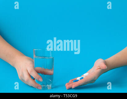 Mani pillole e acqua su uno sfondo blu. Foto Stock