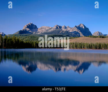 Stati Uniti d'America, Idaho, Sawtooth National Recreation Area, Mt. Heyburn e cime della gamma a dente di sega di riflettere con un po' di scorfano Lago di prima mattina. Foto Stock