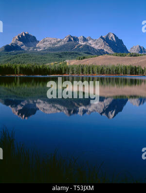 Stati Uniti d'America, Idaho, Sawtooth National Recreation Area, Mt. Heyburn e cime della gamma a dente di sega di riflettere con un po' di scorfano Lago di prima mattina. Foto Stock