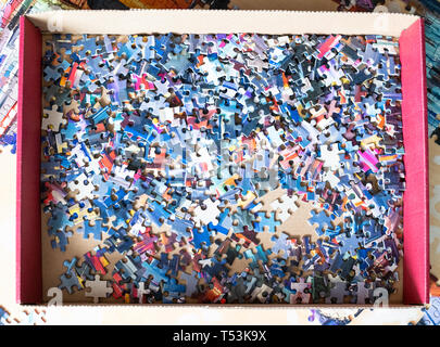 Vista superiore del puzzle smontato i pezzi del puzzle nella casella sul tavolo Foto Stock