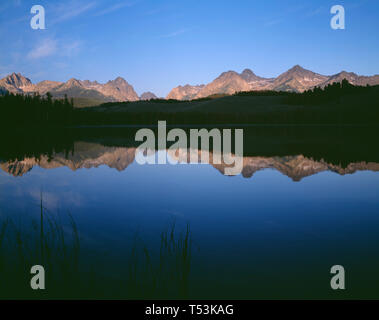 Stati Uniti d'America, Idaho, Sawtooth National Recreation Area, picchi della gamma a dente di sega di riflettere con un po' di scorfano Lago di prima mattina. Foto Stock