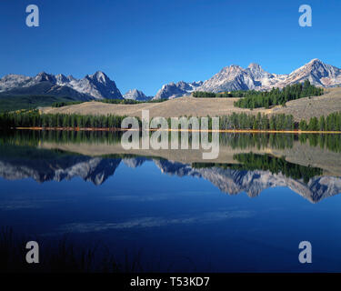 Stati Uniti d'America, Idaho, Sawtooth National Recreation Area, picchi della gamma a dente di sega di riflettere con un po' di scorfano Lago di prima mattina. Foto Stock