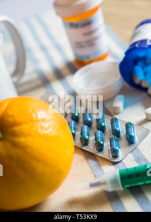 Medicazione durante la colazione, capsule accanto a un arancione, immagine concettuale Foto Stock