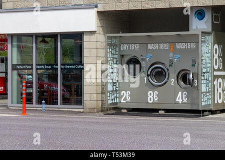 Outdoor self service lavanderia a gettoni, lavatrici accanto a un coffee shop Foto Stock