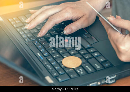 La donna le mani sul computer portatile con bitcoin su tasti e card per acquistare bitcoin. Abstract: shopping online. Foto Stock