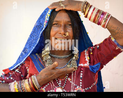 Anziani Lambadi indiano donna (Banjara, Indian gypsy) da Karnataka pone nel suo vestito tradizionale per la telecamera e mostra il suo schiave. Foto Stock