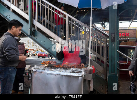 Un Sud Americana donna vendita di carni alla griglia da un cavalletto sotto la sopraelevata treni della metropolitana . In corona, Queens, NYC Foto Stock