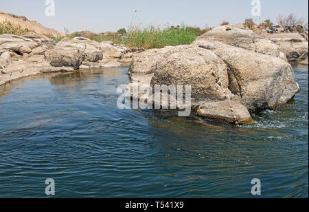 Barca a vela downriver Nilo in Aswan Egitto attraverso il paesaggio rurale paesaggio con acqua fluente round rocciosa isola di cataratta closeup Foto Stock