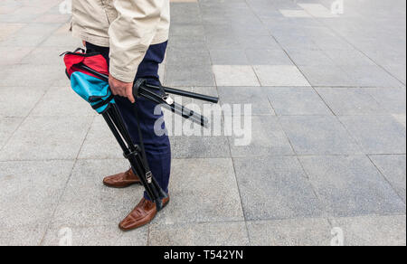 Uomo che porta due portatile e pieghevole sgabelli a Siviglia Foto Stock