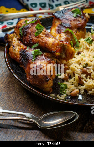 Cucina africana grigliate di cosce di pollo con riso jollof con orzo e black eyed peas Foto Stock