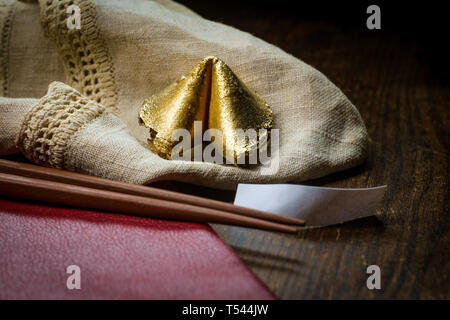 Fascino fortunato golden fortune cookie con bacchette e dark moody concetto di illuminazione Foto Stock