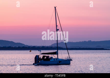 Uno yacht di vele al di fuori del porto di Porthcawl all'alba su una calma, marea alta. Foto Stock