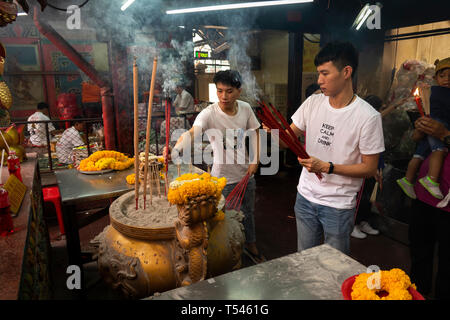 Thailandia, Bangkok, Thanon Tanao, Khwaeng San Chao Pho Sua, Xuantian Shangdi tempio, due maschi giovani adoratori pregando, posizionando i bastoncini di incenso a shri Foto Stock