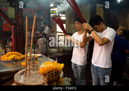 Thailandia, Bangkok, Thanon Tanao, Khwaeng San Chao Pho Sua, Xuantian Shangdi tempio, due maschi giovani adoratori pregando, tenendo i bastoncini di incenso ay shri Foto Stock