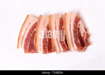 Più fresco e succose fette di pancetta giacciono su un bianco sfondo neutro. La pancetta è pronto per l'uso in scrittura per molti piatti. Foto Stock