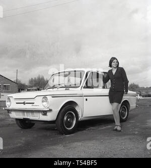 1967, storico, giovane donna che indossa un capo di lana cardigan e gonna in posa accanto a un Sunbeam Sport autovettura, la versione sportiva della famosa piccola auto, HIllman Imp. Hillman Imp è stata una piccola autovettura realizzato dal gruppo Rootes e il suo successore Chrysler Europa dal 1963 fino al 1976 è stato il concorrente nella piccola auto categoria per il Mini. Foto Stock