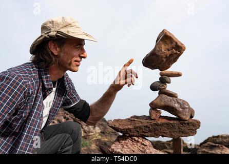 Dunbar, Scotland, Regno Unito. Xx Apr, 2019. Pedro Duran esamina la sua scultura in Eye Cave Beach in Dunbar durante il giorno di apertura del Parlamento di pietra Campionato di impilamento 2019. Credito: Iain Masterton/Alamy Live News Foto Stock