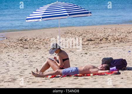 Bournemouth Dorset, Regno Unito. 21 apr 2019. Regno Unito: meteo canicola continua con caldo e soleggiato, come testa beachgoers al mare per godere del calore e del sole a Bournemouth spiagge per le vacanze di Pasqua - metà mattina e già le spiagge sono sempre imballati, come sunseekers arrivarci presto per ottenere il loro spazio. Matura a prendere il sole sotto ombrellone. Credito: Carolyn Jenkins/Alamy Live News Foto Stock