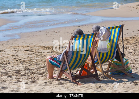 Bournemouth Dorset, Regno Unito. 21 apr 2019. Regno Unito: meteo canicola continua con caldo e soleggiato, come testa beachgoers al mare per godere del calore e del sole a Bournemouth spiagge per le vacanze di Pasqua - metà mattina e già le spiagge sono sempre imballati, come sunseekers arrivarci presto per ottenere il loro spazio. Matura in sedie a sdraio - torna in vista posteriore Credito: Carolyn Jenkins/Alamy Live News Foto Stock