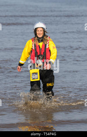 Bagnino RNLI femminile a Blackpool, Lancashire. 21 aprile 2019. Meteo nel Regno Unito. Il sole inizia la giornata sulla costa mentre la gente si reca sul lungomare per un leggero esercizio fisico e per godersi la brezza marina in quello che si prevede sia il giorno più caldo delle vacanze di Pasqua. I bagnini e l'equipaggio della scialuppa di salvataggio uniscono le forze in esercitazioni presso il punto caldo locale. Foto Stock