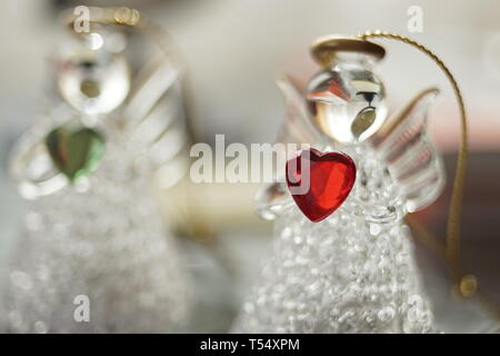 Due statuette trasparente di piccoli angeli con cuori nelle loro mani Foto Stock