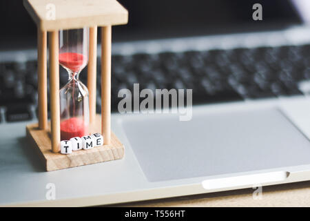 Sabbia timer clock sul laptop con 'tempo' alfabeto lettera cubo .simbolo del tempo Foto Stock