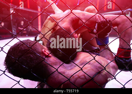 Il concetto di sport di combattimento senza regole.due boxer atleti nell'arena della scena ottagonale. Una alternativa guardare il pugilato combatte attraverso la meta Foto Stock