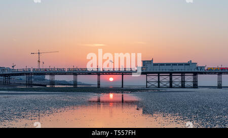 Worthing Sussex, Regno Unito; xx aprile 2019; Dawn con il sorgere del sole dietro a Worthing Pier a bassa marea Foto Stock