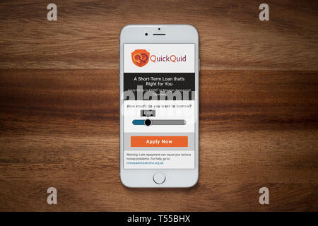 Un iPhone che mostra la rapida Quid sito poggia su una semplice tavola di legno (solo uso editoriale). Foto Stock