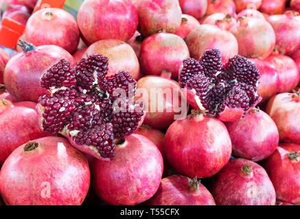 Mature e frutti rossi melograno e diviso in quattro parti, contro lo sfondo di melograno frutto rivestita in righe Foto Stock