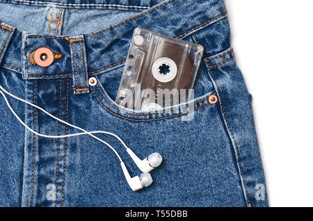 Cassetta Audio in una tasca di un vecchio stile jeans blu e cuffie isolato su uno sfondo bianco. Foto Stock