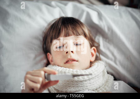 Ragazza con un freddo misura la temperatura Foto Stock