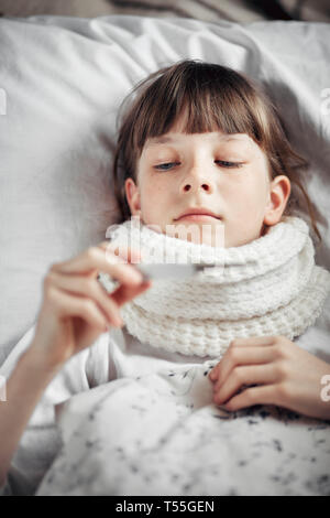 Ragazza con un freddo misura la temperatura Foto Stock