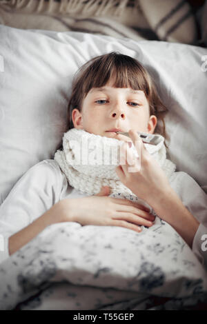 Ragazza con un freddo misura la temperatura Foto Stock