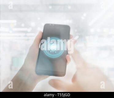 Shopping basket su uno schermo di cellulare. Donna mano azienda telefono cellulare sul supermercato blur sullo sfondo Foto Stock