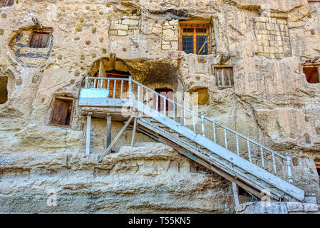 Ferro bianco scale che portano ad uno dei naturalmente fresco, pietra scolpita depositi lungo con molti pigeon loft per concime su una roccia calcarea in Ermen Foto Stock