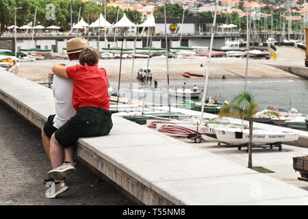 FUNCHAL, Madeira, Portogallo - 22 luglio 2018: turisti non identificato, un uomo e una donna in un luminoso camicetta, sedersi abbracciando sul lungomare di Funchal. Cou Foto Stock