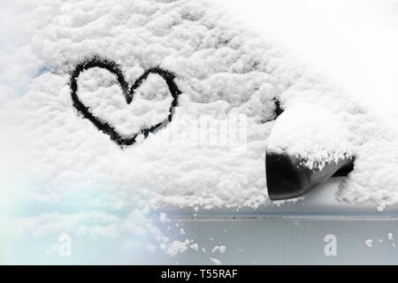 Cuore disegnato in presenza di neve sul vetro per auto Foto Stock