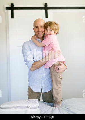 Padre e figlio abbracciando in camera da letto Foto Stock