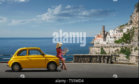 Donna che mantiene mappa poggiando su giallo auto in Atrani, Italia Foto Stock