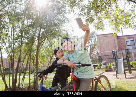 Fratelli tenendo selfie su biciclette Foto Stock