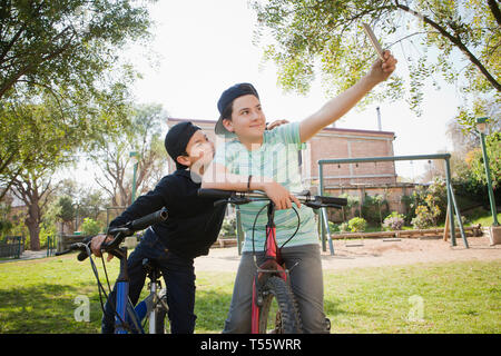 Fratelli tenendo selfie su biciclette Foto Stock