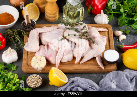Il pollo crudo sul tagliere circondato da ingredienti Foto Stock