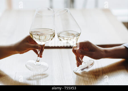 Le mani delle donne la tostatura con bicchieri di vino bianco Foto Stock