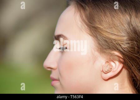 Close-up di mani femminili di mettere protesi in orecchio. Digitali moderne nell'orecchio udito aiuti per la sordità e il disco di pazienti udenti. Foto Stock