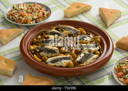 Marocchino tradizionale Tagine con sarde a beccafico, insalata e pane sul tavolo per la cena Foto Stock