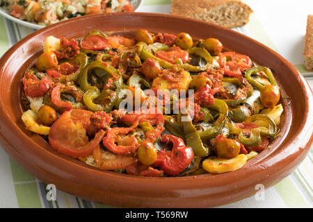 Tradizionale Tagine marocchino con le sardine, le verdure e il pane sulla tavola per la cena Foto Stock